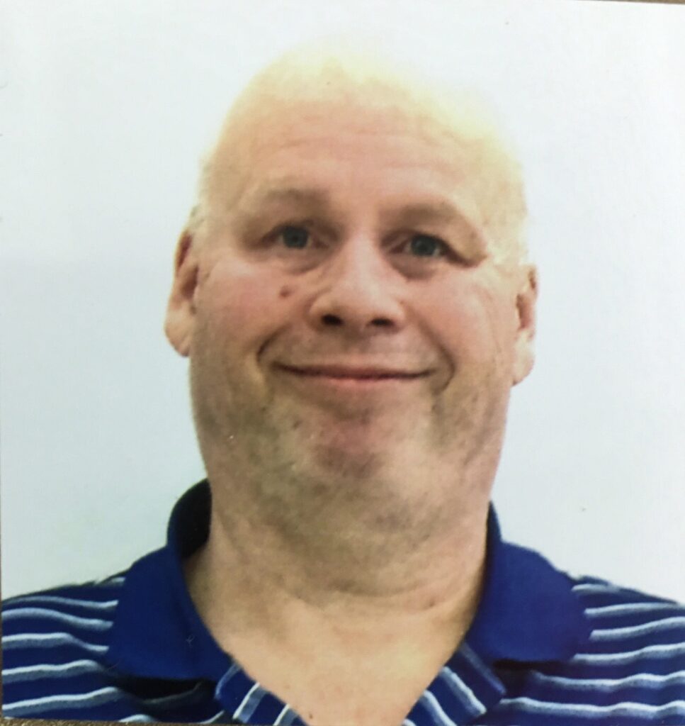 A man with white hair and blue striped shirt.