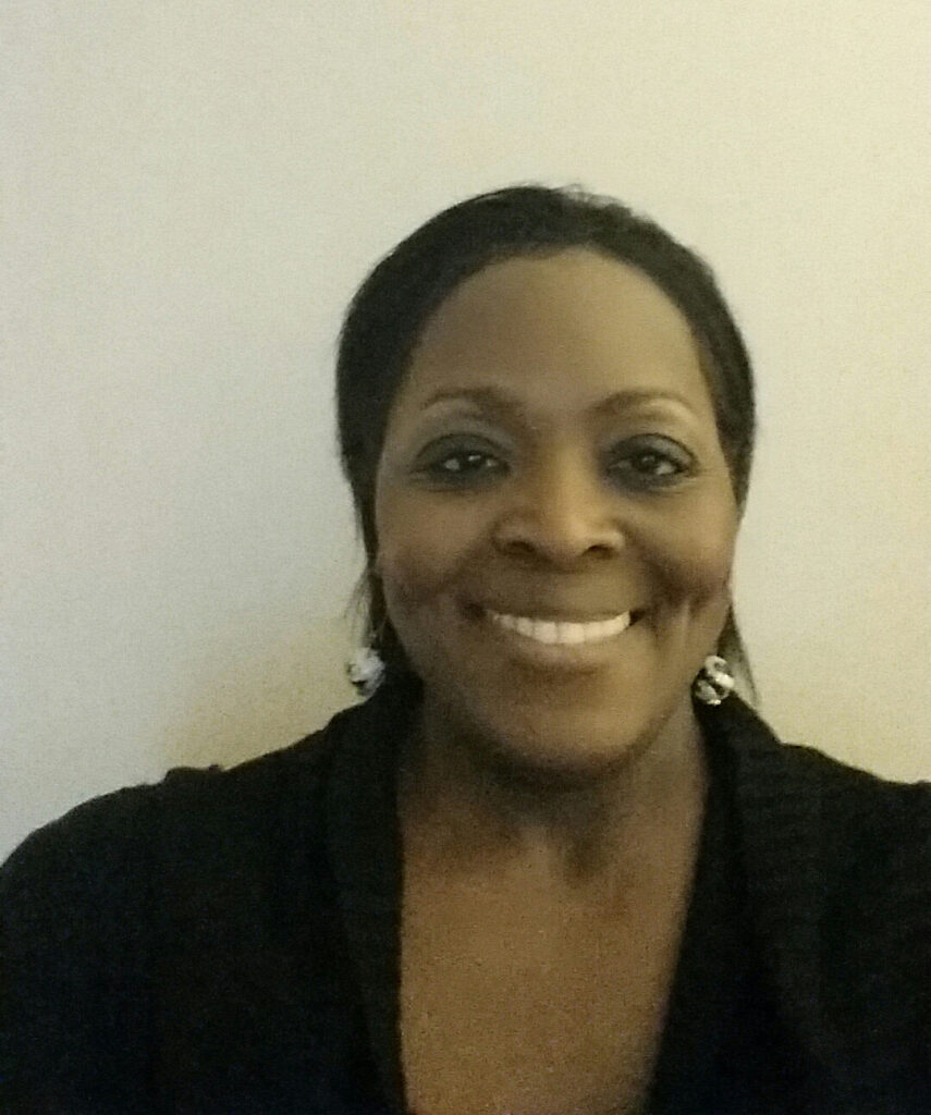 A woman smiling for the camera with her hair in front of a wall.