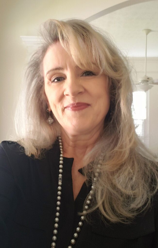 A woman with long gray hair wearing a black shirt.