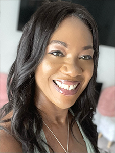 A woman smiling for the camera with long black hair.