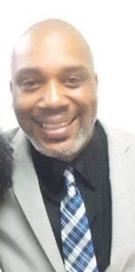 A man in a suit and tie smiling for the camera.
