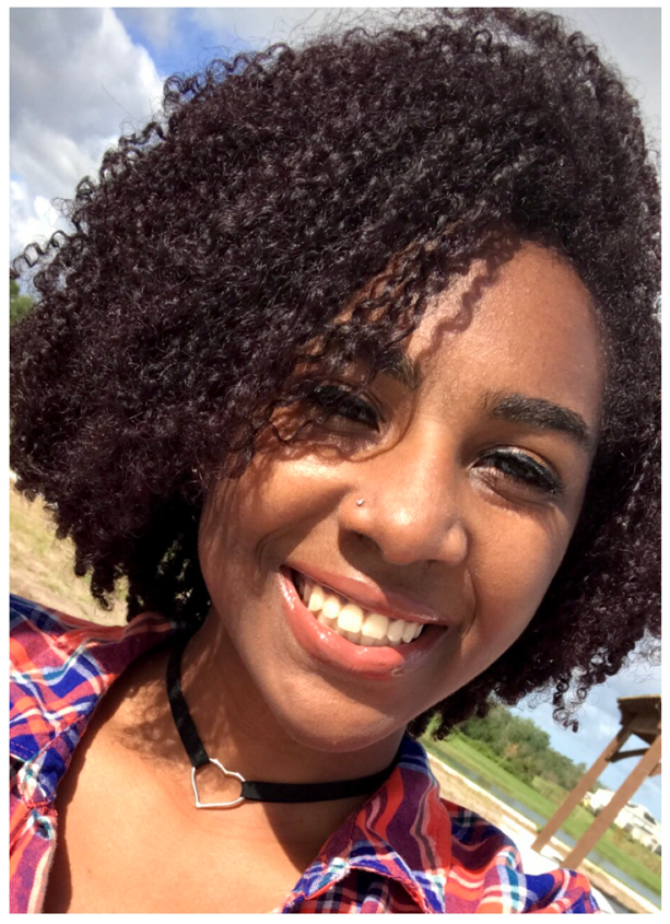 A woman with curly hair smiling for the camera.